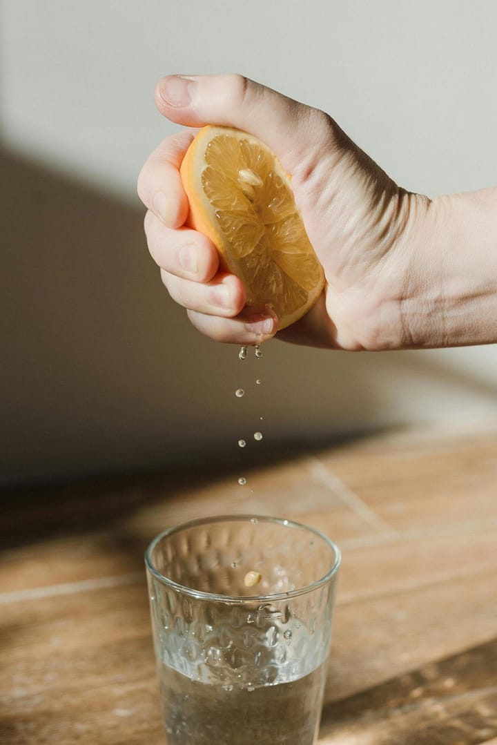 photo of lemon being squeezed into glass of water