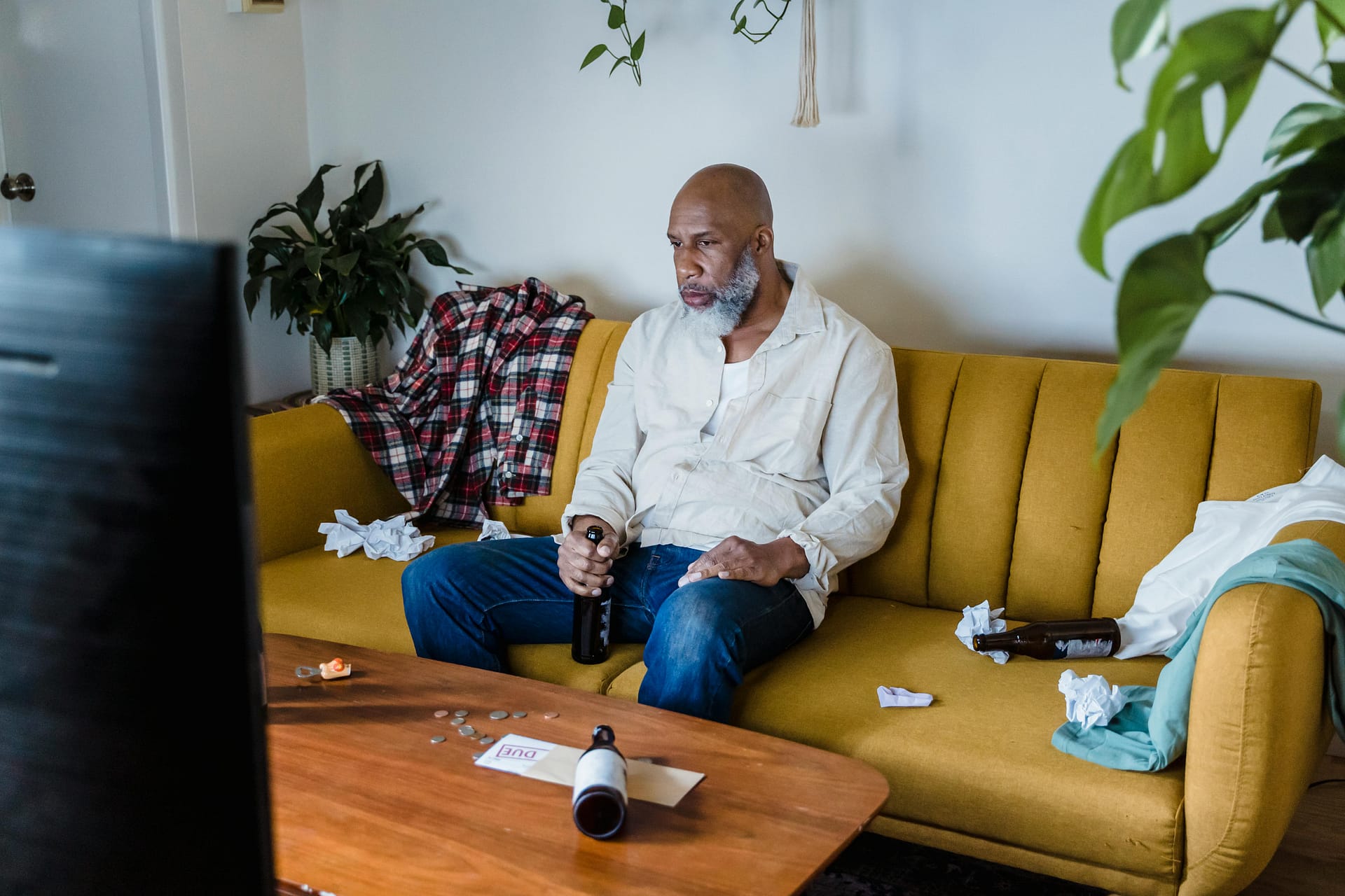 Image of man sat on couch, making excuses